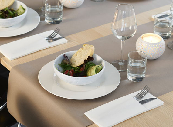 White napkin pockets set on restaurant table with table runner