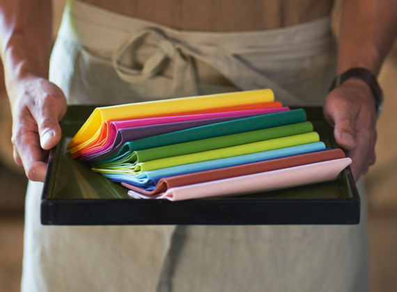 Waiter holding colourful linen feel napkins on a tray