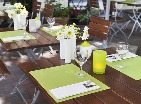 Green silicone reusable placemats on an outdoor restaurant table