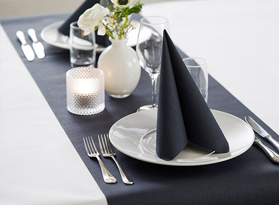 Folded black linen feel napkin on a matching table runner