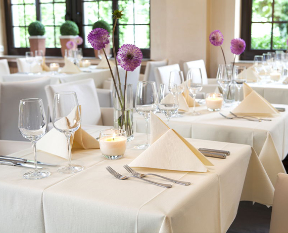 Fully set restaurant tables with linen feel tablecloths